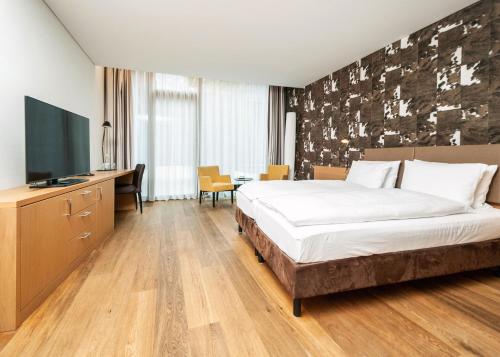 a hotel room with a bed and a flat screen tv at Tailormade Hotel SIHLPARK Schindellegi in Schindellegi