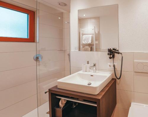 a white bathroom with a sink and a shower at Hotel Garni Almjur in Sankt Anton am Arlberg