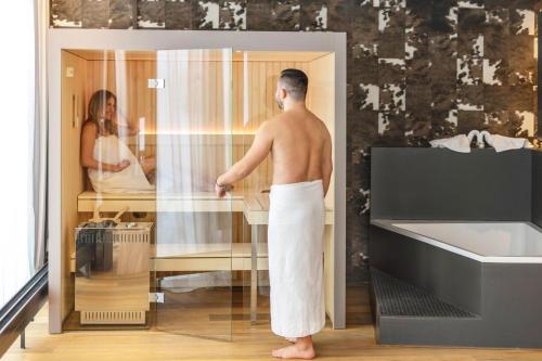 un homme debout dans une salle de bains donnant sur un miroir dans l'établissement Tailormade Hotel SIHLPARK Schindellegi, à Schindellegi