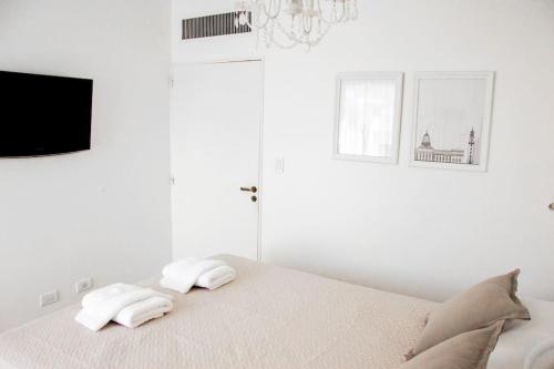 Un dormitorio blanco con una cama con toallas. en Center Apart - a metros Obelisco en Buenos Aires