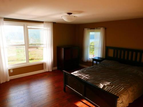 1 dormitorio con 1 cama y 2 ventanas en Vineyard Farmhouse with Hot Tub & Lake Views en Hammondsport