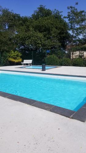 ein blauer Pool mit einer Bank daneben in der Unterkunft Résidence Belle Vue YourHostHelper in Arcachon