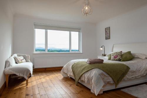 a bedroom with a bed and a chair and a window at Clai Cerrig in Llangefni