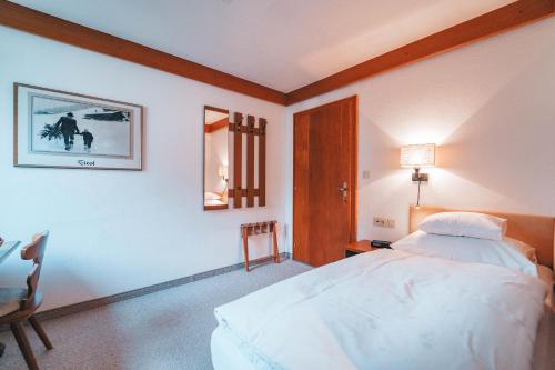 a bedroom with a bed and a table and a lamp at Hotel Garni Almjur in Sankt Anton am Arlberg