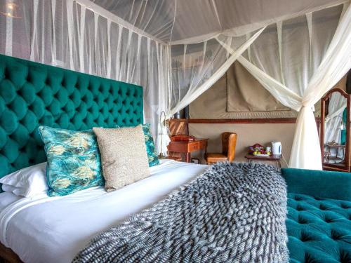 a bedroom with a large bed with a blue headboard at Tintswalo Siankaba in Livingstone