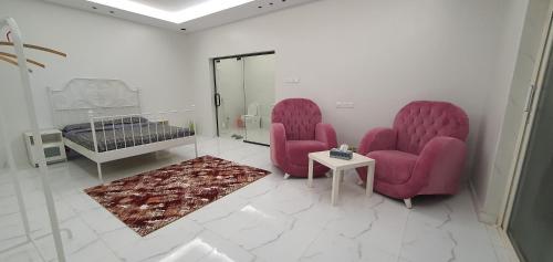two pink chairs and a bed in a room at Challet Orlando park استراحة اورلاندو in Al Mundassah