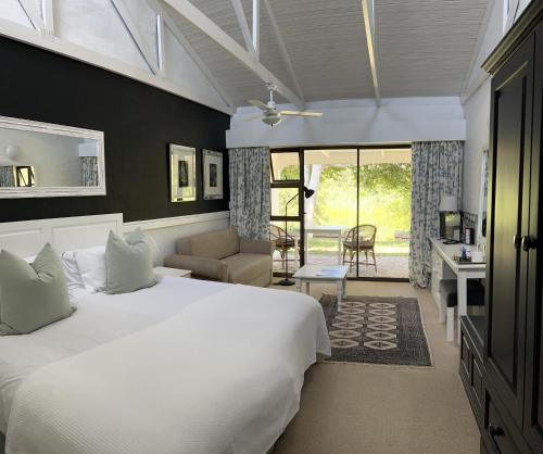 a bedroom with a large white bed and a living room at Bitou River Lodge in Plettenberg Bay