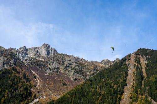 un parapente survole une chaîne de montagnes dans l'établissement Majestic Alpin - A luxurious apartment with a nordic feel, à Chamonix-Mont-Blanc