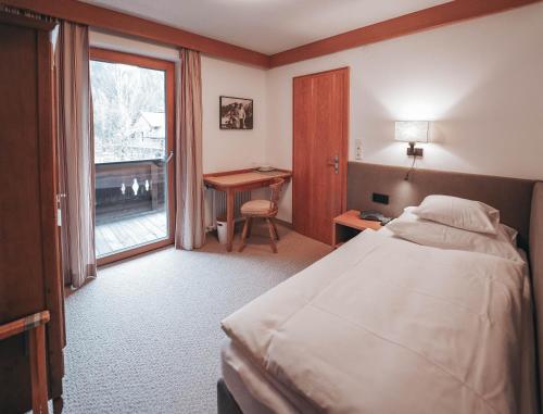 a bedroom with a bed and a desk and a window at Hotel Garni Almjur in Sankt Anton am Arlberg