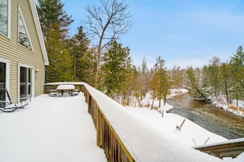 a house with a snow covered balcony next to a river at Plattitudes in Honor