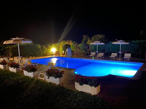 a swimming pool with chairs and umbrellas at night at Hotel Janas in Tertenìa