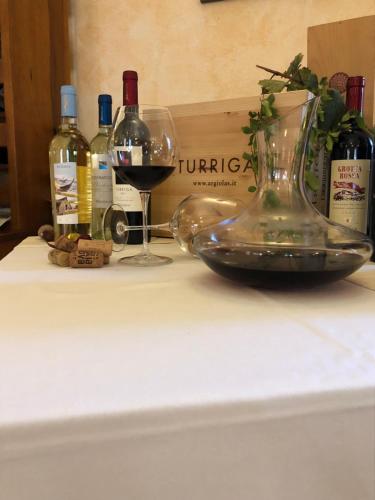 a table with a bottle of wine and a glass at Hotel Janas in Tertenìa