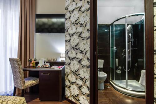 bagno con doccia e tavolo con sedia di Catone District Hotel a Roma