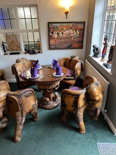 a dining room with a table and chairs with purple hats at Siam cottage guesthouse over 300 years old with Thai restaurant in Moreton in Marsh
