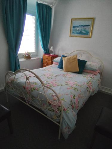 a bedroom with a bed with a floral blanket and a window at Applebys Guest House in Holyhead