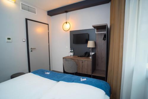 a bedroom with a bed and a desk with a television at Hotel Palatinus in Sopron