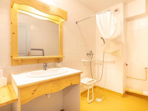 La salle de bains est pourvue d'un lavabo et d'une douche avec un miroir. dans l'établissement Les Grizzlis - 22 - Appart montagne PMR - 4 pers, à Saint-Sorlin-dʼArves