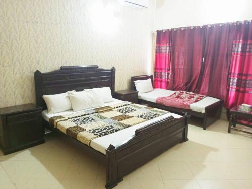 a bedroom with two beds and red curtains at Sunrising Guest House Islamabad in Islamabad