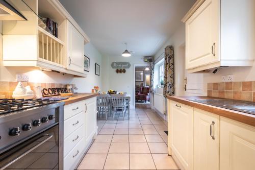 a kitchen with white cabinets and a stove top oven at Rustic cabin located in a serene forest setting in Southampton