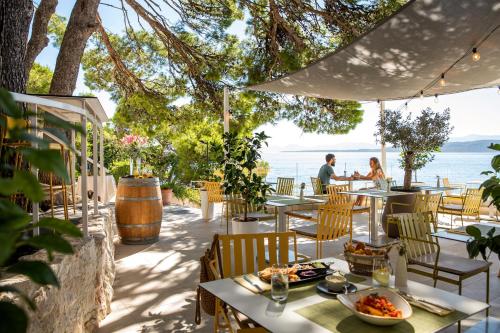 een restaurant met tafels en stoelen en uitzicht op de oceaan bij TUI BLUE Makarska - Adults Only in Igrane