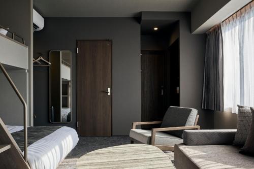鹿児島市にあるFAV HOTEL KAGOSHIMACHUOのベッドルーム1室(ベッド1台、ソファ、椅子付)