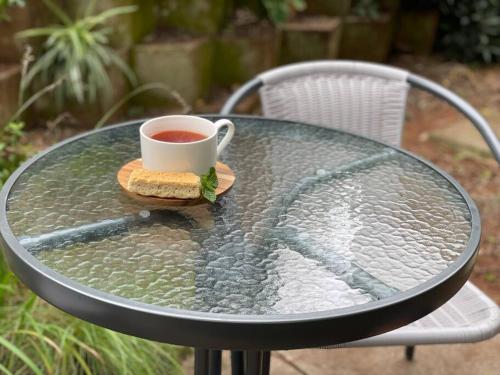 un tavolo di vetro con una tazza di tè e un panino di Ladybird a Durban