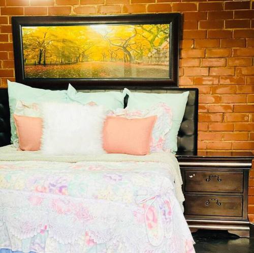 a bed with pink pillows and a painting above it at Ladybird in Durban