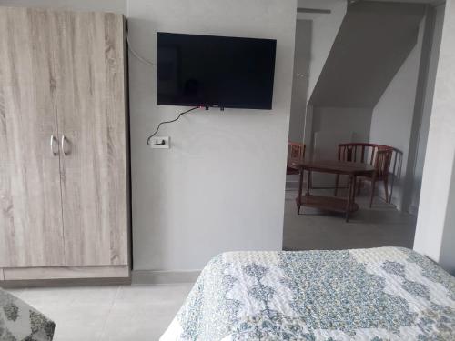 1 dormitorio con 1 cama y TV en la pared en Casa Hostal Paso por La Serena, en La Serena