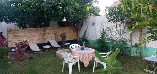 a garden with a table and chairs and a fence at flowerhouse Sukuta Gambia in Sukuta