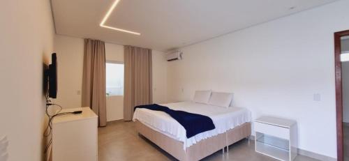 1 dormitorio con 1 cama y TV en Suítes bem equipadas e uma hidromassagem para relaxar, en Porto Seguro
