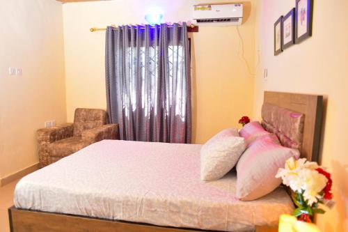 a bedroom with a bed with a chair and a window at Living Green APARTMENTS AIRPORT PICK UP in Benin City