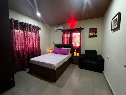 a bedroom with a bed and a chair in it at Living Green APARTMENTS AIRPORT PICK UP in Benin City