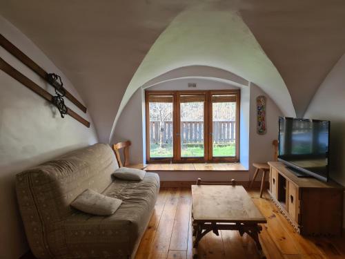 Una sala de estar con un sofá y un televisor. en Le Préau, en Ornon