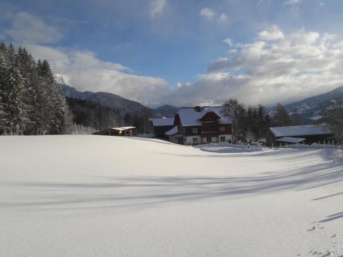 a snow covered hill with a house in the background at Forsterhof in Haus im Ennstal