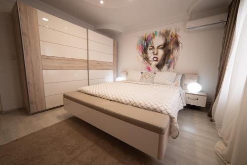 um quarto com uma cama com um quadro de uma mulher em JelenaR em Novi Sad