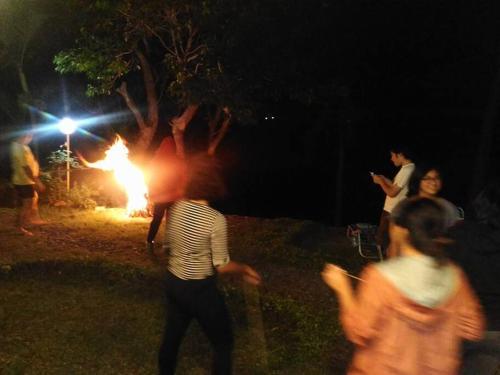 een groep mensen die 's nachts rond een vuur staan bij Anilao Cliffhouse in Mabini