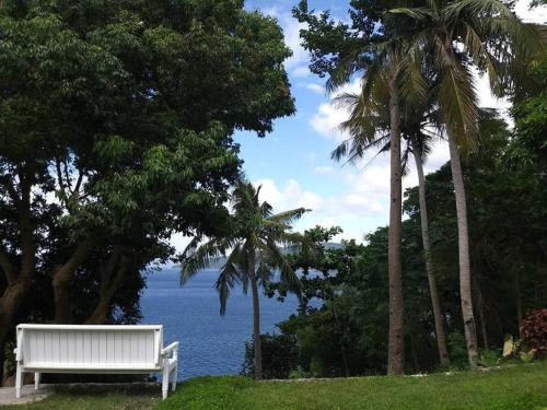 a white bench sitting in the grass near the water at Anilao Cliffhouse in Mabini