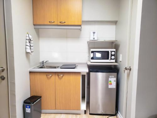 a small kitchen with a sink and a microwave at Hostal Paso por La Serena in La Serena