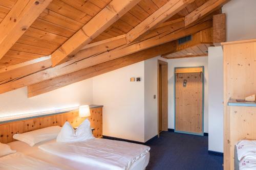 a bedroom with two beds in a room with wooden ceilings at La Roccia Wellness Hotel in Cavalese