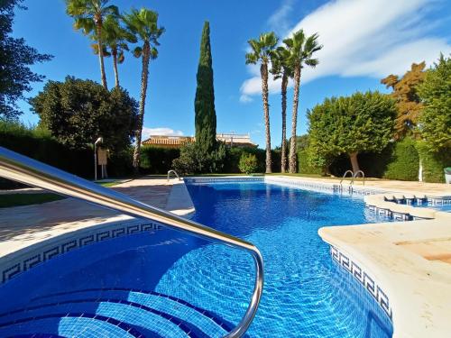 una piscina con palme sullo sfondo di Butterfly Bungalow - 9009 a Los Alcázares