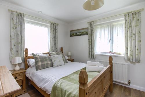 a bedroom with a bed and two windows at Queen Bower Farm Lodge in Alverstone