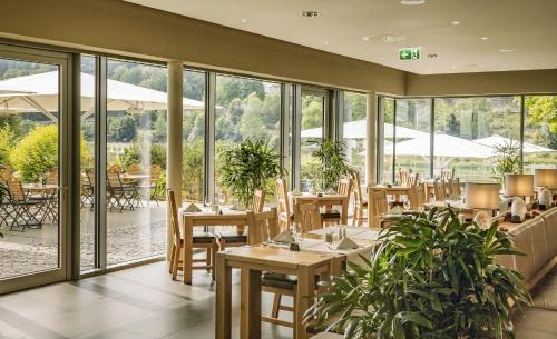 un restaurante con mesas, sillas y ventanas en Hotel Elbresidenz an der Therme en Bad Schandau