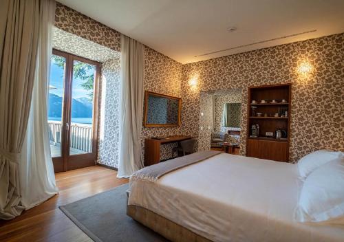 una camera con un grande letto e una grande finestra di Villa Lario Resort Mandello a Mandello del Lario