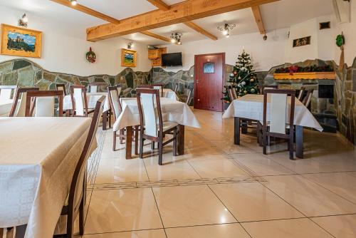 a restaurant with tables and chairs and a christmas tree at willapieninska in Kluszkowce