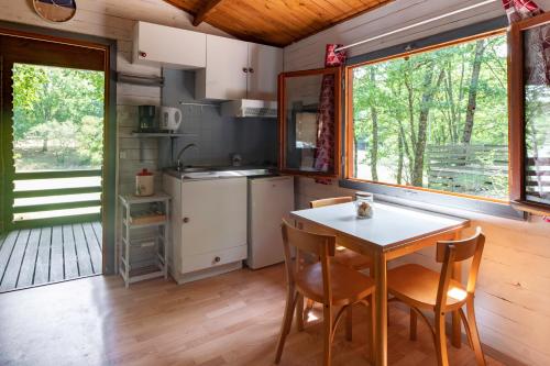 a kitchen with a table and chairs in a cabin at Camping les Lacs d'Armagnac in Bretagne-dʼArmagnac