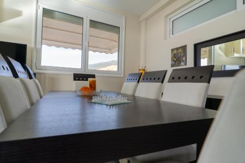a dining room with a black table and white chairs at Villa Sea View in Volos