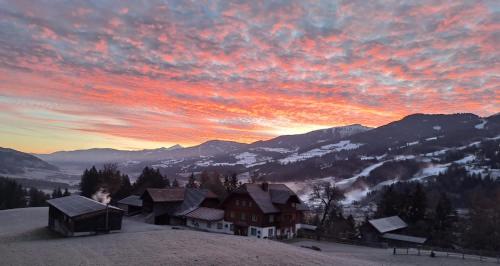 a house on a snow covered hill with a sunset at Forsterhof in Haus im Ennstal