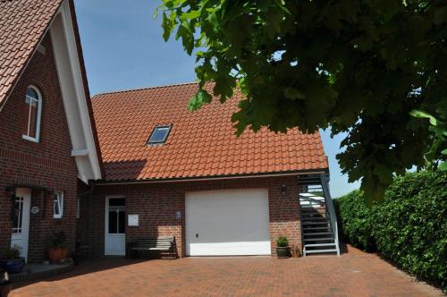 a brick house with a garage with a white garage door at Ferienwohnung Martens 65344 in Moormerland