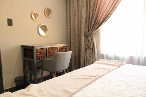a bedroom with a bed and a chair and a window at The Villa 442 in Pretoria