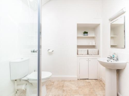a white bathroom with a toilet and a sink at The Nest in Helmsley